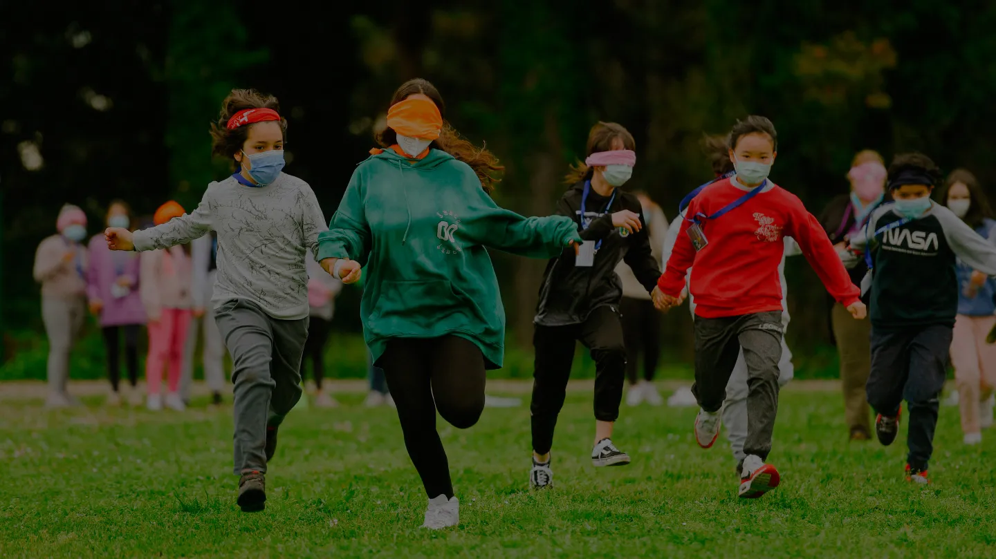 Niños y jóvenes corriendo juntos al aire libre como parte de una actividad de Enki.
