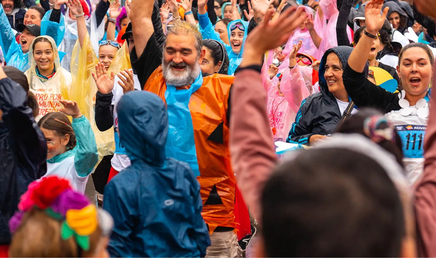 Multitud diversa celebrando la salida de la Carrera ENKI bajo la lluvia