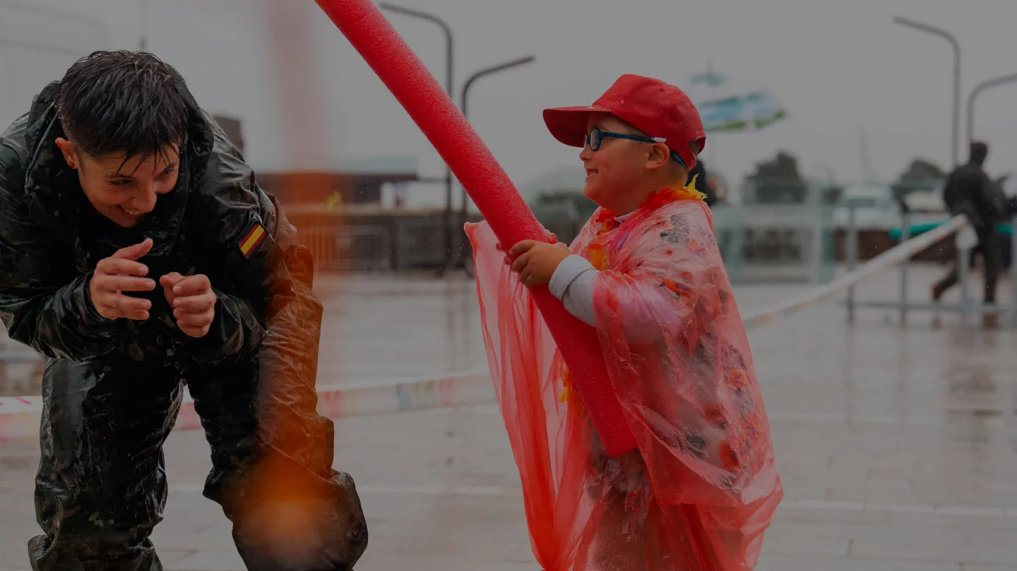 Un niño y un adulto compartiendo un momento lúdico al aire libre bajo la lluvia durante una actividad de Enki.